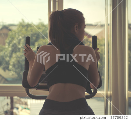 Woman running on treadmill facing out the windows 37709232
