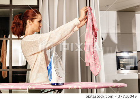 Red-haired young beautiful woman ironing clothes 37710049