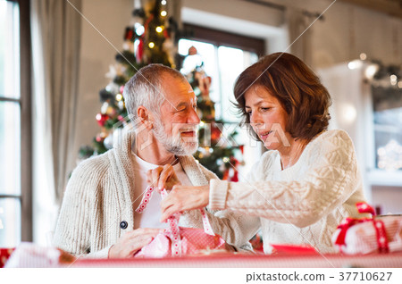 Senior couple in sweaters wrapping Christmas gifts Senior couple in sweaters wrapping Christmas gifts 37710627