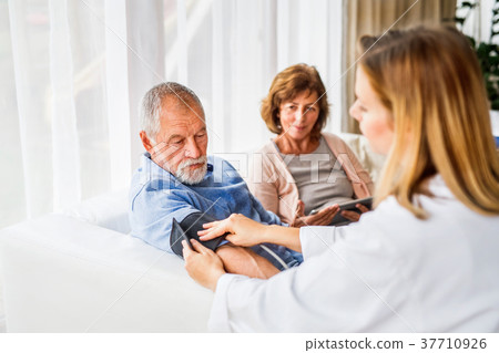 Female doctor checking blood pressure of senior Female doctor checking blood pressure of senior 37710926
