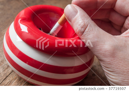 man crushing a cigarette on red ashtray man crushing a cigarette on red ashtray 37719307