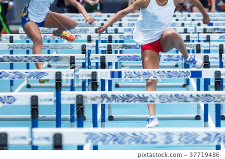 Two high school girls racing the hurdles Two high school girls racing the hurdles 37719486