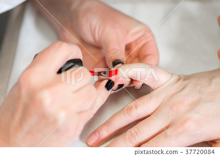 Manicure. Master applies varnish drawing on nails 37720084