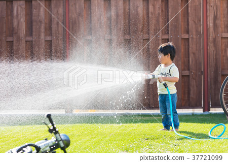 Boy playing with water in the garden Boy playing with water in the garden 37721099