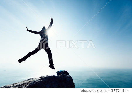 free hiker jumping on sunrise seaside cliff edge free hiker jumping on sunrise seaside cliff edge 37721344