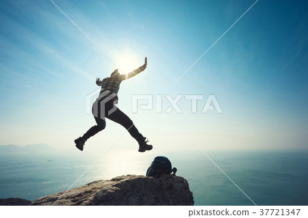 free hiker jumping on sunrise seaside cliff edge free hiker jumping on sunrise seaside cliff edge 37721347