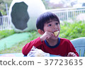 Boy eating snack at park 37723635