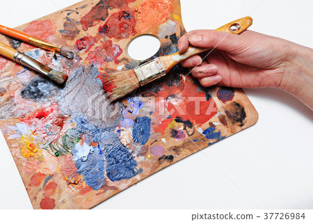 Artist's hand with brushes and palette of colors Artist's hand with brushes and palette of colors 37726984