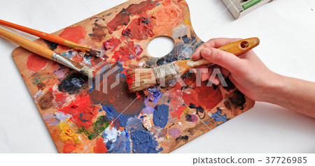 Artist's hand with brushes and palette of colors Artist's hand with brushes and palette of colors 37726985