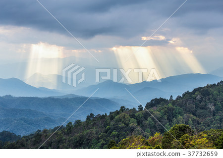 Sunbeam shining through cloudy sky to mountain 37732659