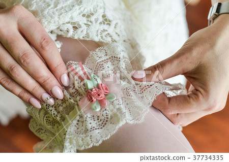 Bride's garter on the leg. Beautiful bride sitting Bride's garter on the leg. Beautiful bride sitting 37734335