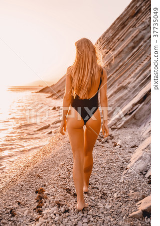 Attractive woman in black bikini walk on beach 37735049