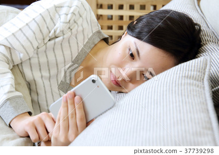 A woman watching a smartphone in her bedroom 37739298