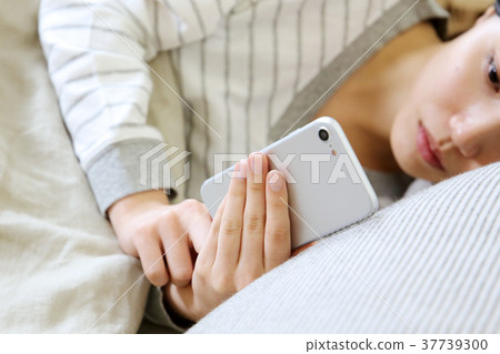 A woman watching a smartphone in her bedroom 37739300