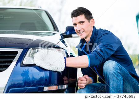 Smiling man cleaning the headlamp on his car Smiling man cleaning the headlamp on his car 37746692