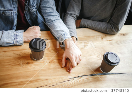 Students couple having a romatic lunch indoors holding hands close-up Students couple having a romatic lunch indoors holding hands close-up 37748540