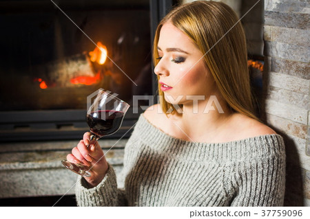 Girl drinking wine by the fireplace 37759096