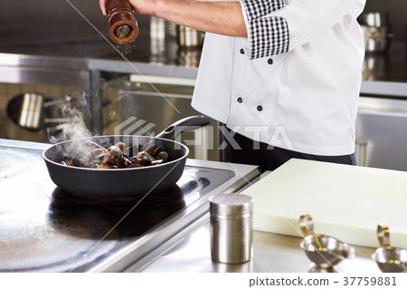 Chef peppering oven-steamed mussels in pan. 37759881