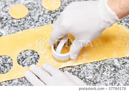 Making round holes on dough using metal form. Making round holes on dough using metal form. 37760178