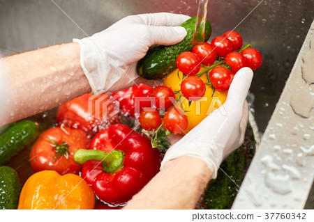 Washing vegetablea in a sink. 37760342