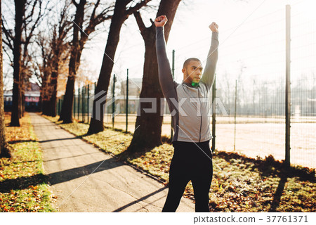 Sportsman warming up before run in autumn park 37761371