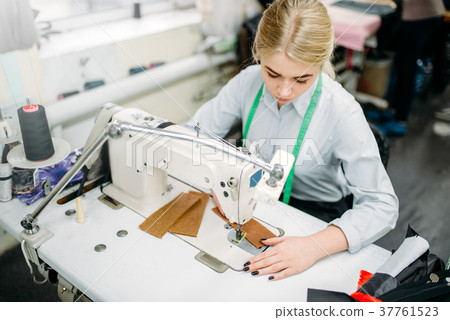 Needlewoman sews fabrics on a sewing machine 37761523