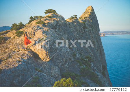 Woman in red dress walking on rock 37776112