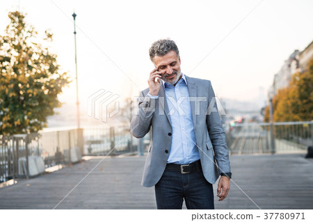 Mature businessman with smartphone in a city. Mature businessman with smartphone in a city. 37780971