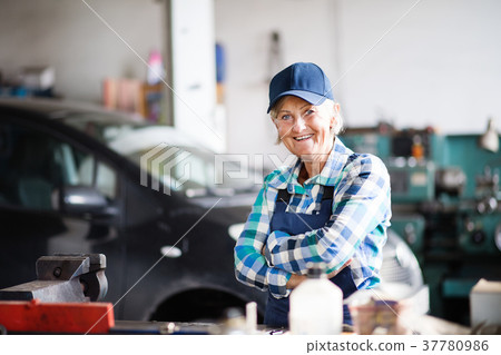 Senior female mechanic repairing a car in a garage 37780986