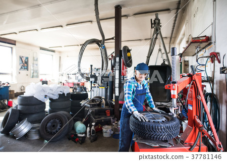 Senior female mechanic repairing a car in a garage Senior female mechanic repairing a car in a garage 37781146