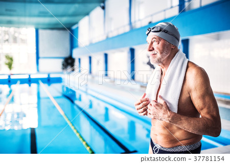 Senior man standing by the indoor swimming pool. Senior man standing by the indoor swimming pool. 37781154