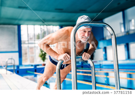 Senior man stretching by the indoor swimming pool. Senior man stretching by the indoor swimming pool. 37781158