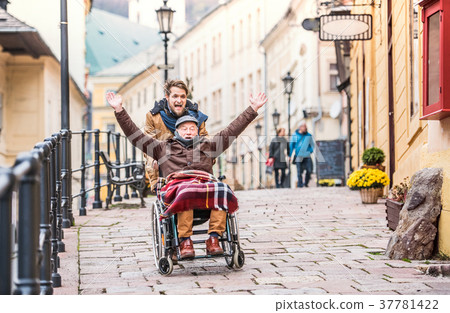 Senior father in wheelchair and young son on a Senior father in wheelchair and young son on a 37781422
