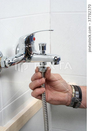 Plumber repairing a faucet in a bathroom Plumber repairing a faucet in a bathroom 37782370
