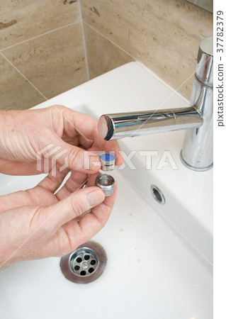 Plumber repairing a faucet filter in a bathroom 37782379