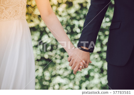 The bride and groom join hands. 37783581