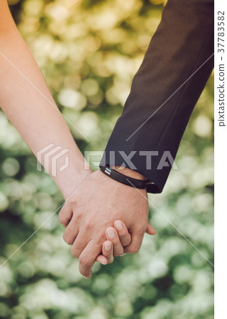 The bride and groom hold hands together. The bride and groom hold hands together. 37783582