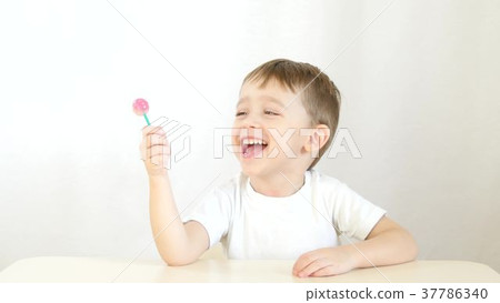 Happy child smiling and eating lollipops on a Happy child smiling and eating lollipops on a 37786340