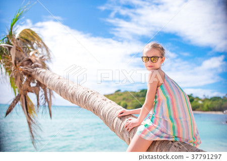 Adorable little girl sitting on palm tree during 37791297