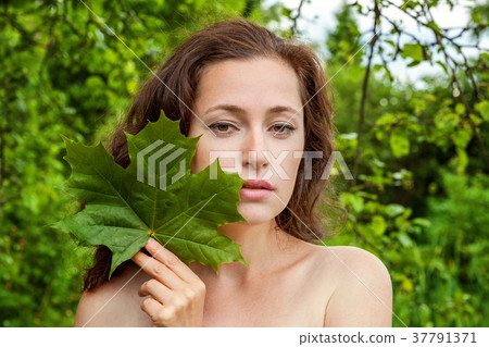Girl with the leaf in her hand in a park 37791371