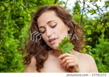 Girl with the leaf in her hand in a park 37791372