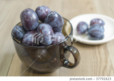 blue plum lies in a glass on a table 37791623
