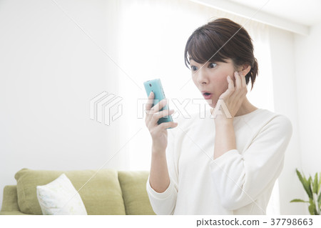A woman looking at her smartphone in the living room A woman looking at her smartphone in the living room 37798663