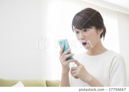 A woman looking at her smartphone in the living room A woman looking at her smartphone in the living room 37798667