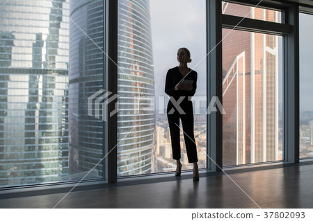 Business woman holding a tablet and standing in a 37802093