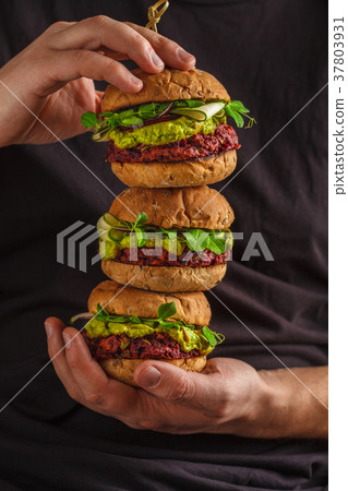Vegan healthy burgers in mans hands.  37803931