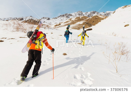 A group of three freeriders climb the mountain for 37806576