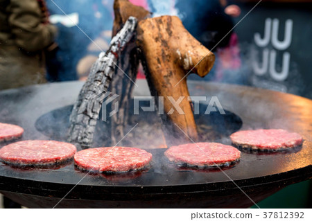 Meat patties prepared on circle grill outdoors Meat patties prepared on circle grill outdoors 37812392