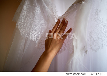 Female hand touches wedding dress close up Female hand touches wedding dress close up 37812413