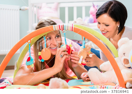 Women furnishing baby room preparing play bar for Women furnishing baby room preparing play bar for 37816941